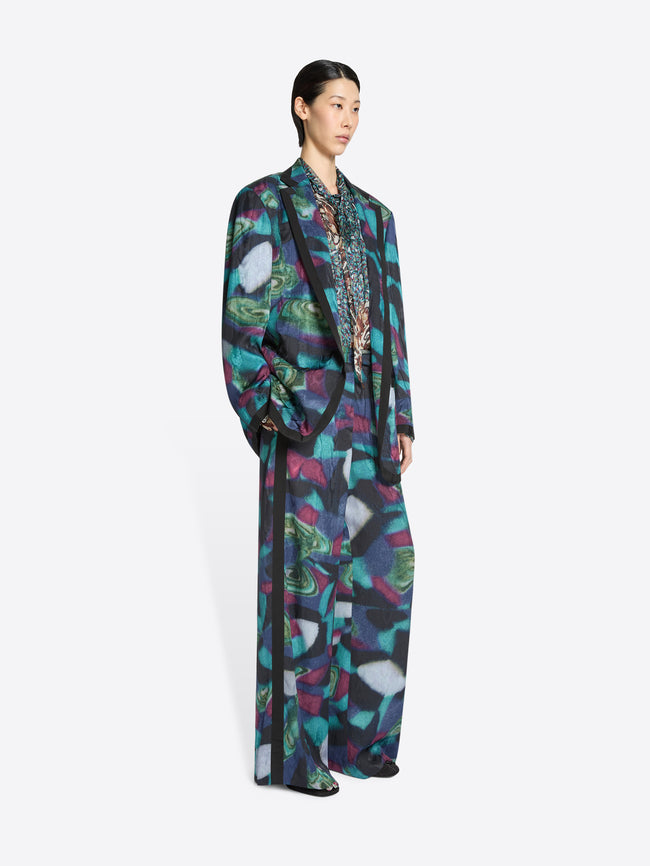 Model wearing a long, patterned blazer and matching pants on a white background