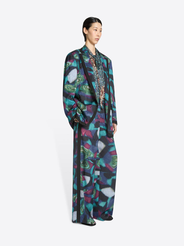 Model wearing a long, patterned blazer and matching pants on a white background