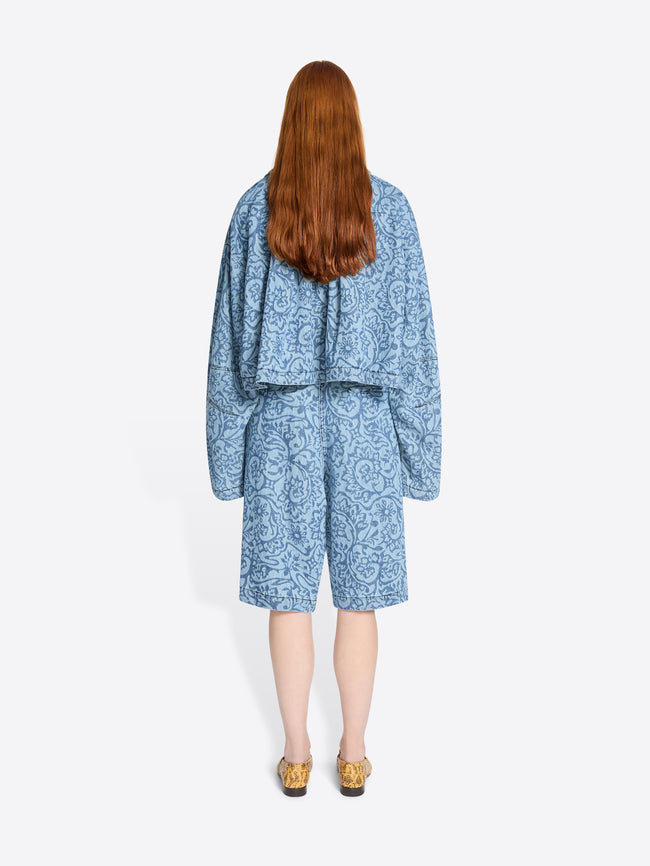 Back view of a person wearing a blue patterned outfit on a white background