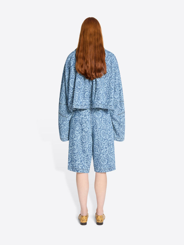 Back view of a person wearing a blue patterned outfit on a white background