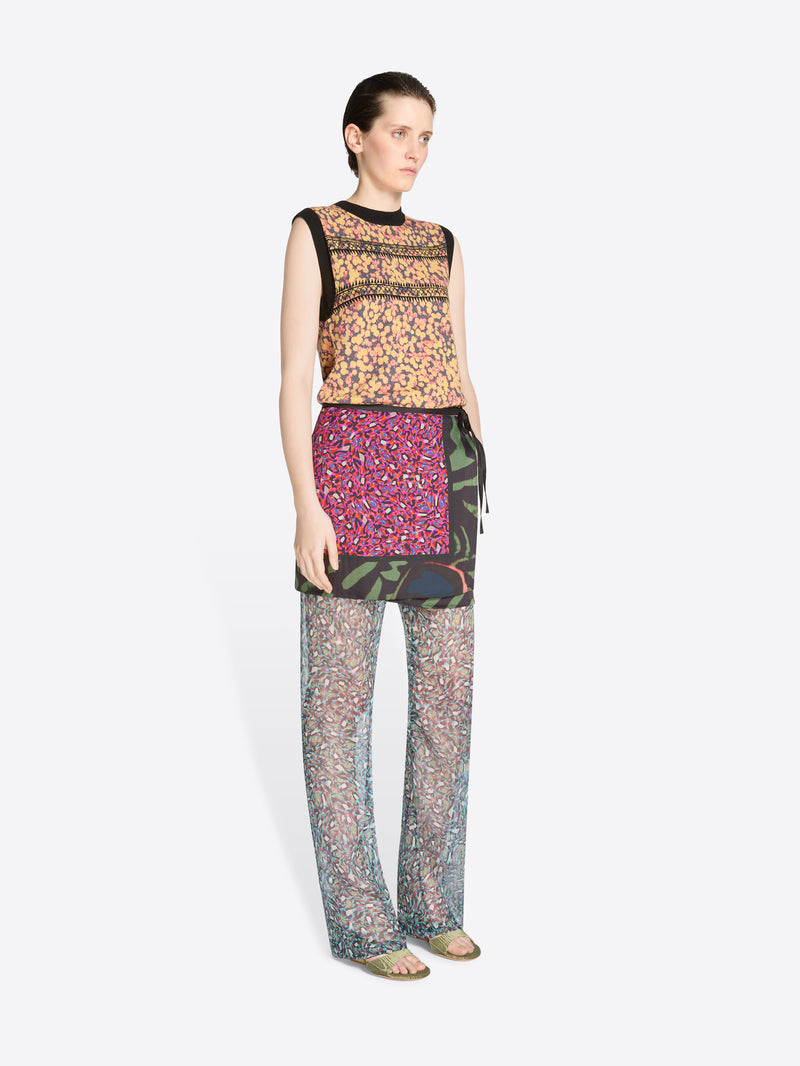 Woman wearing a patterned top, skirt and pants on a white background