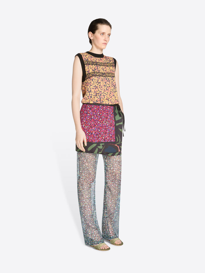 Woman wearing a patterned top, skirt and pants on a white background