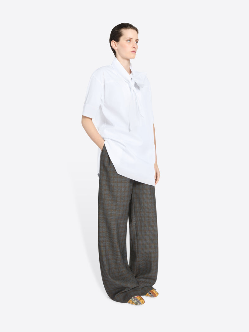 Person wearing a white shirt and gray checkered pants on a white background
