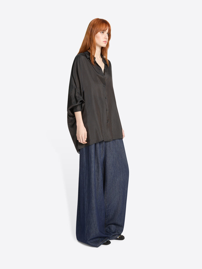Woman wearing a dark brown oversized shirt and blue denim pants on a white background