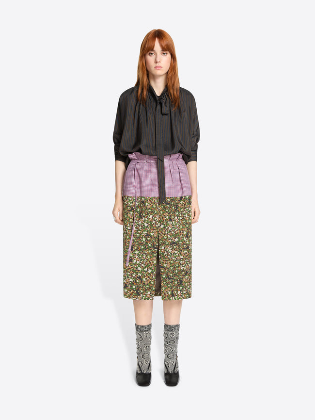 Woman wearing a brown shirt and floral skirt on a white background