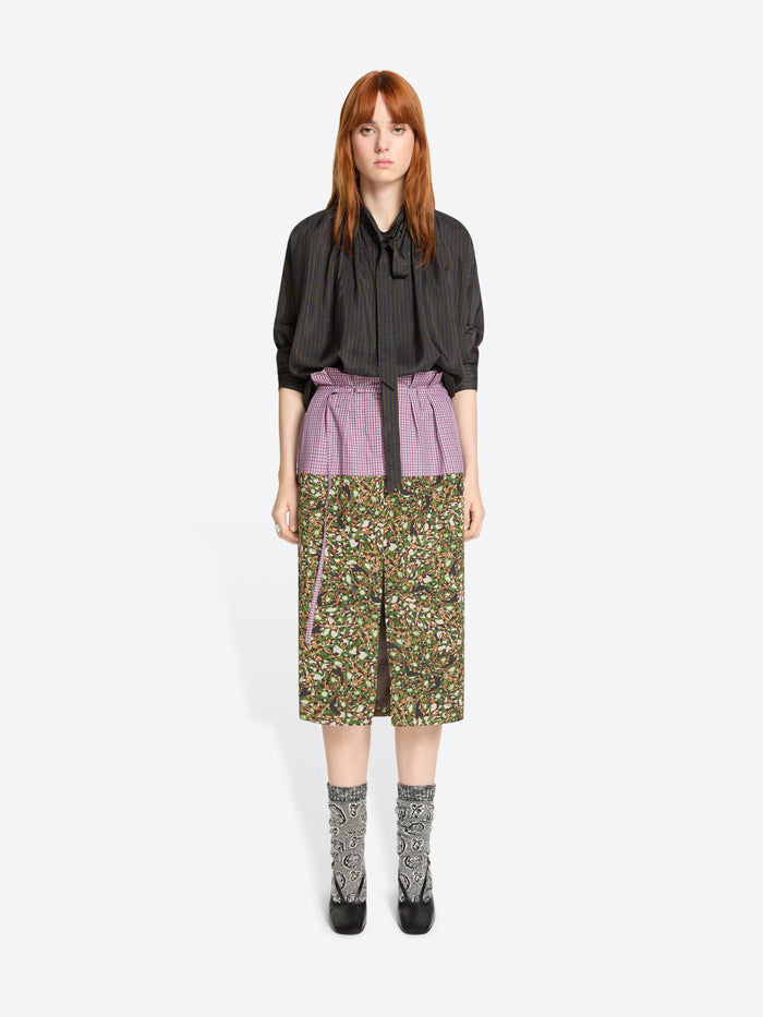 Woman wearing a brown shirt and floral skirt on a white background