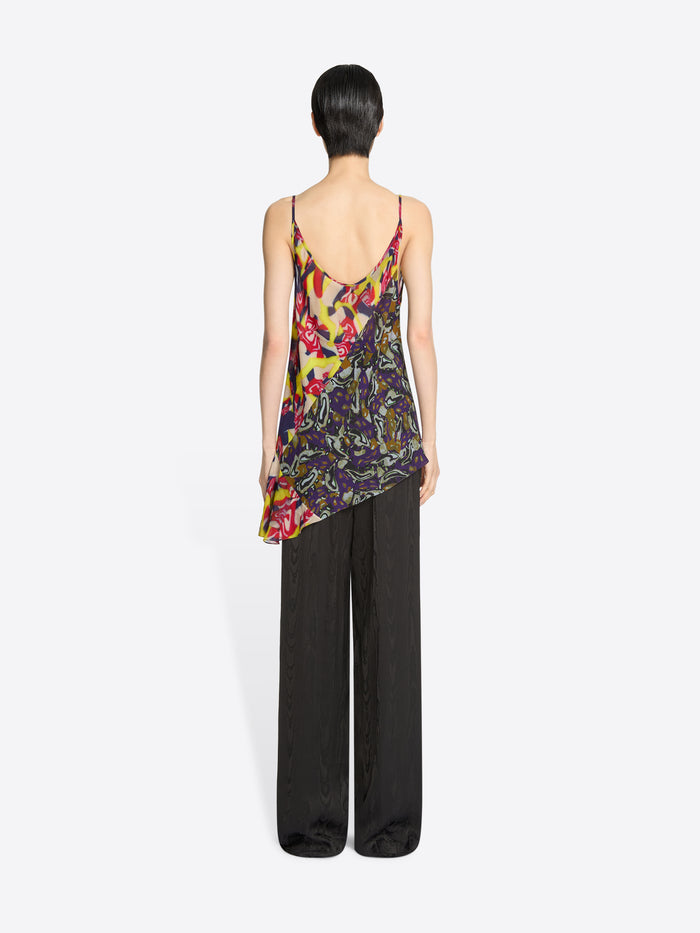 Back view of a woman wearing a colorful floral top and dark brown pants on a white background