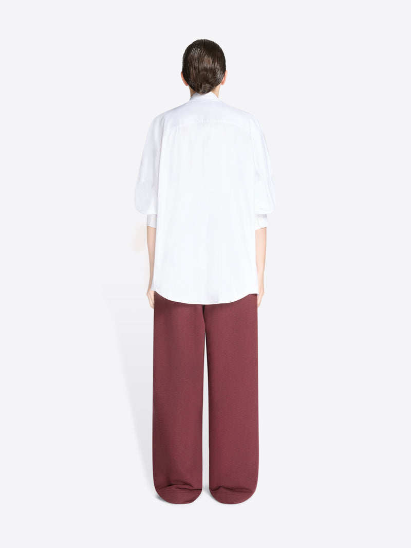 Back view of a person wearing a white shirt and burgundy pants on a white background