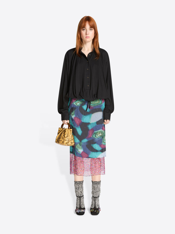 Woman wearing a black shirt and colorful skirt with a white background
