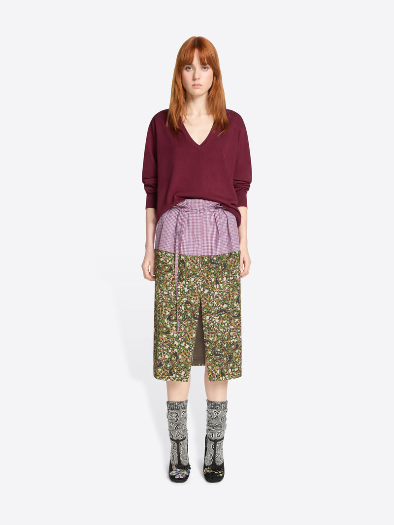 Woman wearing a burgundy sweater and patterned skirt on a white background