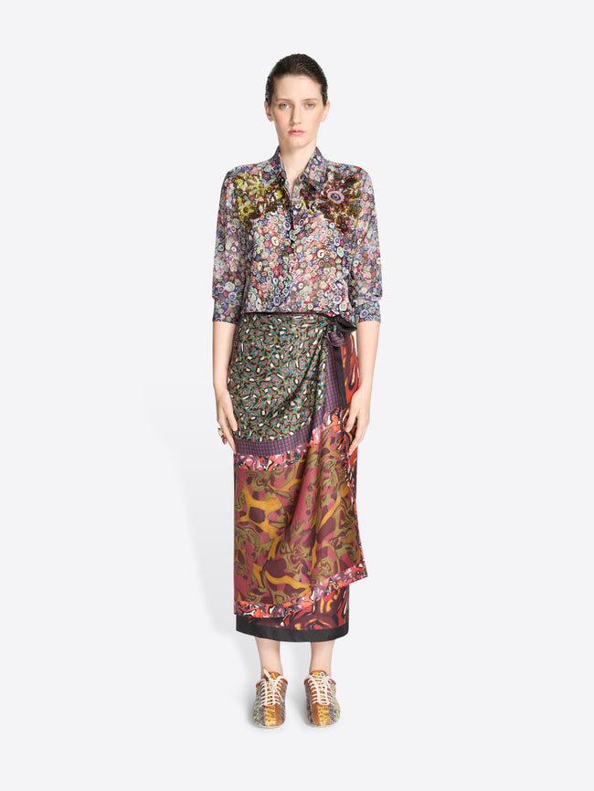 Woman wearing a patterned blouse and skirt on a white background