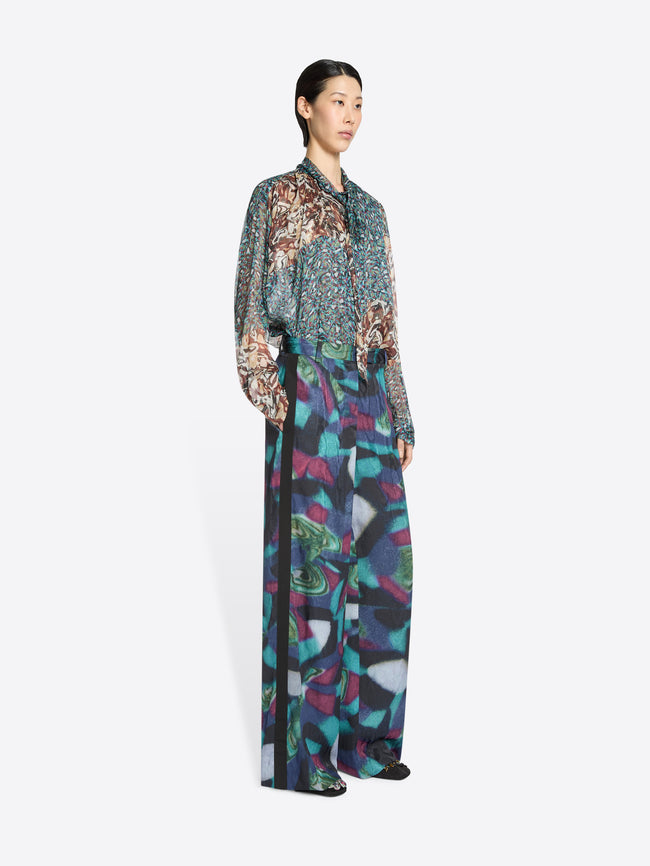 Woman wearing a patterned shirt and a colorful pants on a white background