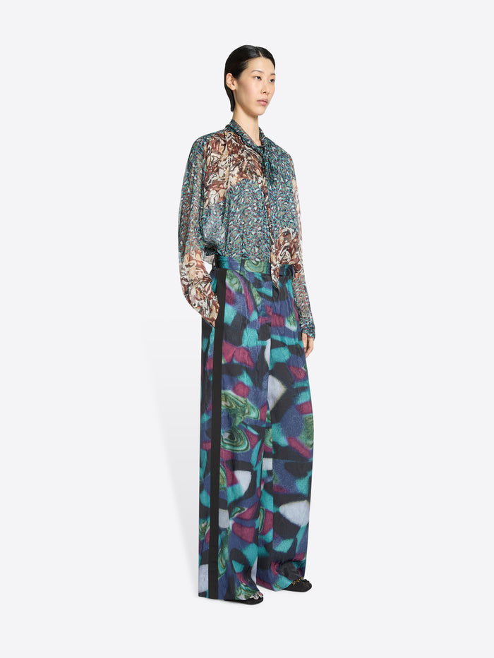 Woman wearing a patterned shirt and a colorful pants on a white background