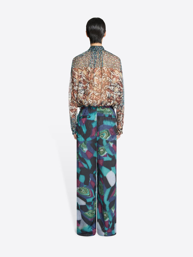Back view of a person wearing a patterned shirt and colorful pants on a white background