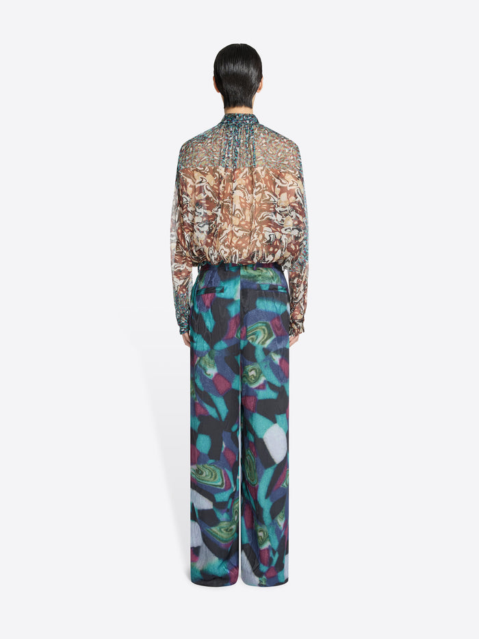 Back view of a person wearing a patterned shirt and colorful pants on a white background