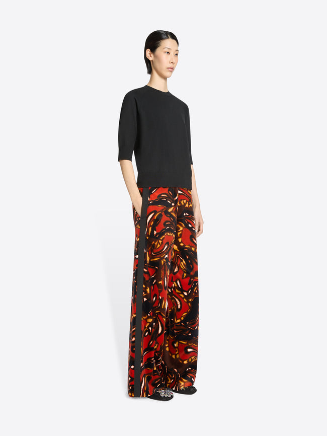 Woman wearing a black top and colorful patterned pants on a white background
