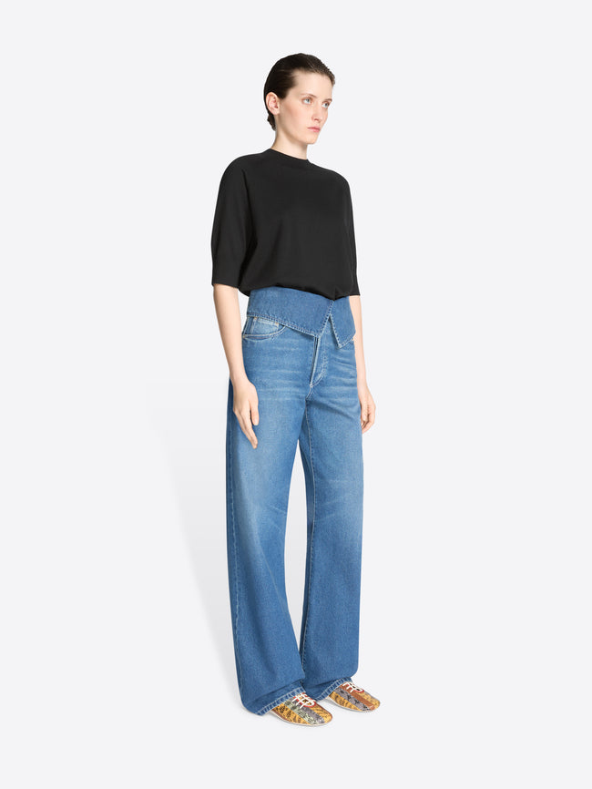 Woman wearing blue jeans and a black top on a white background