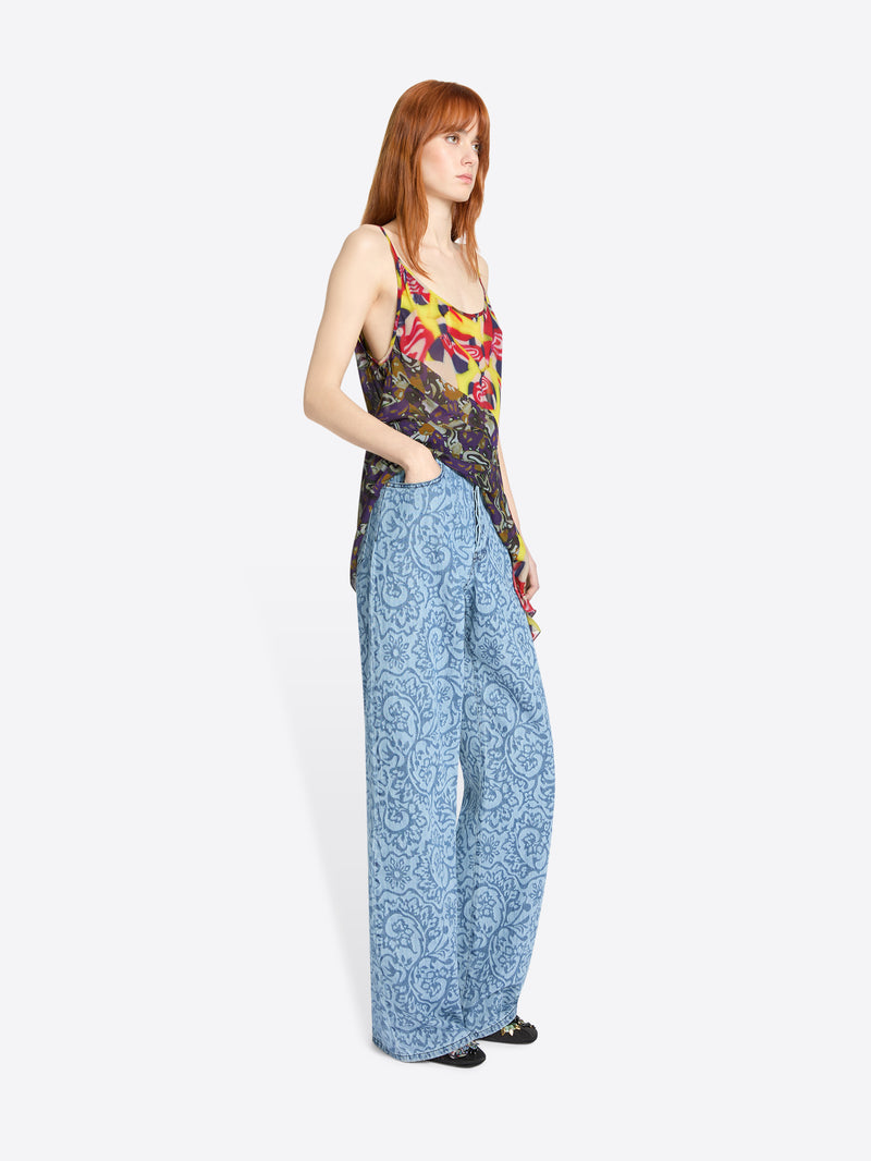 Woman wearing a colorful top and blue patterned pants on a white background