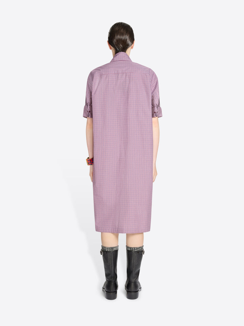 Back view of a person wearing a purple checkered dress on a white background