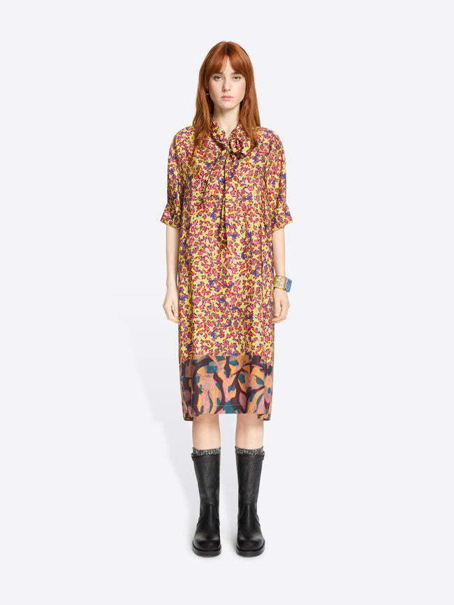 Woman wearing a colorful floral dress with black boots on a white background