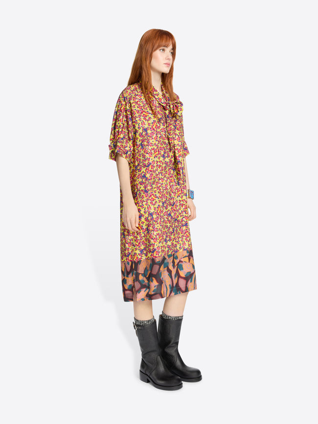 Woman wearing a colorful floral dress and black boots on a white background
