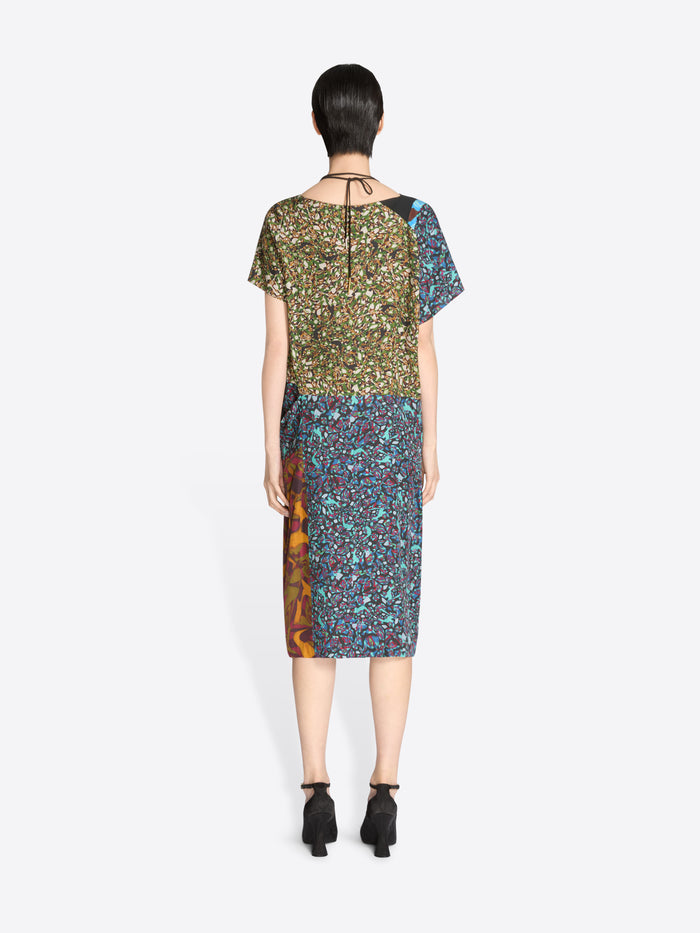 Back view of a woman wearing a patterned dress on a white background
