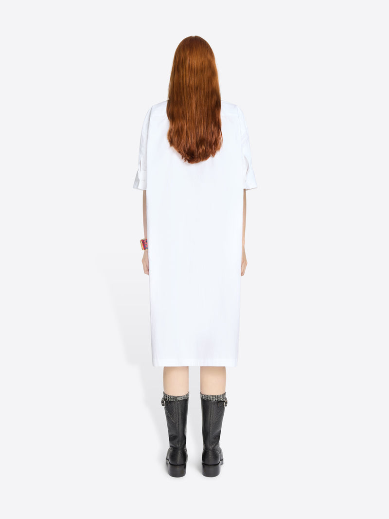 Back view of a person wearing a white dress and black boots on a white background