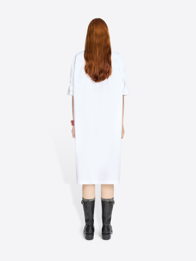 Back view of a person wearing a white dress and black boots on a white background