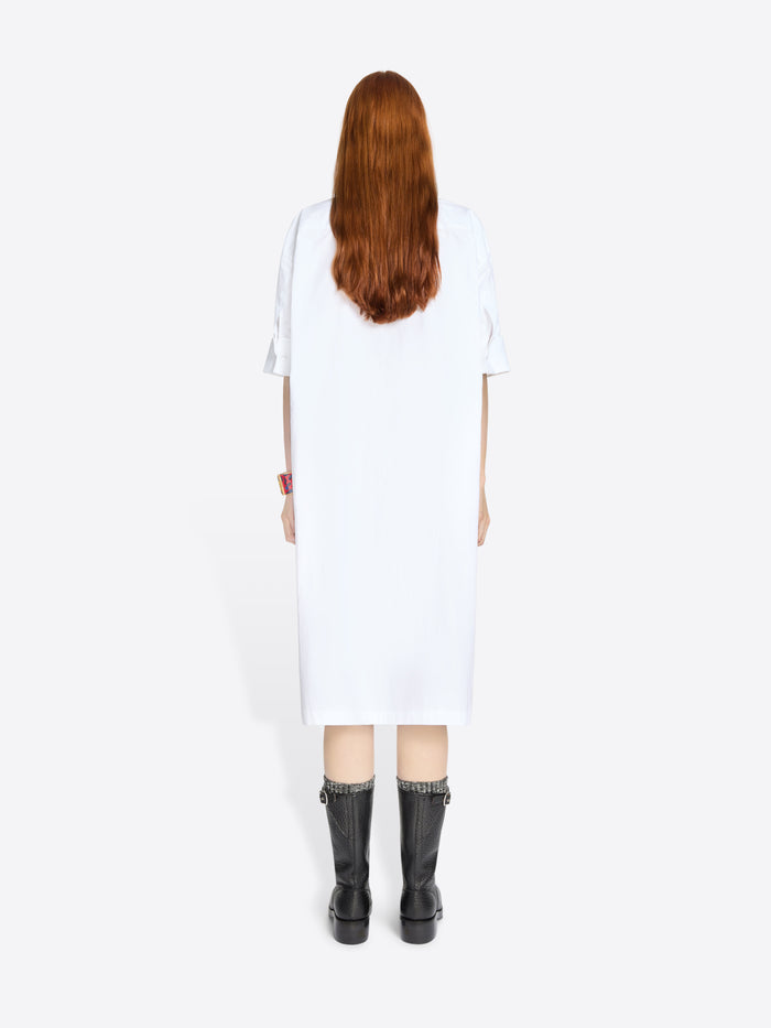 Back view of a person wearing a white dress and black boots on a white background