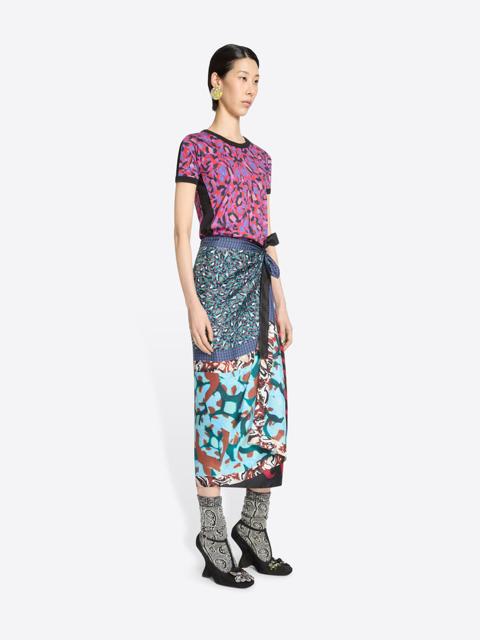 Woman wearing a colorful patterned top and skirt on a white background