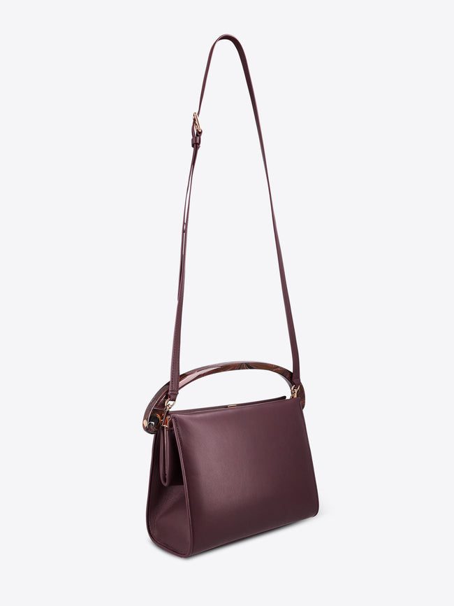 Burgundy leather handbag with a strap on a white background