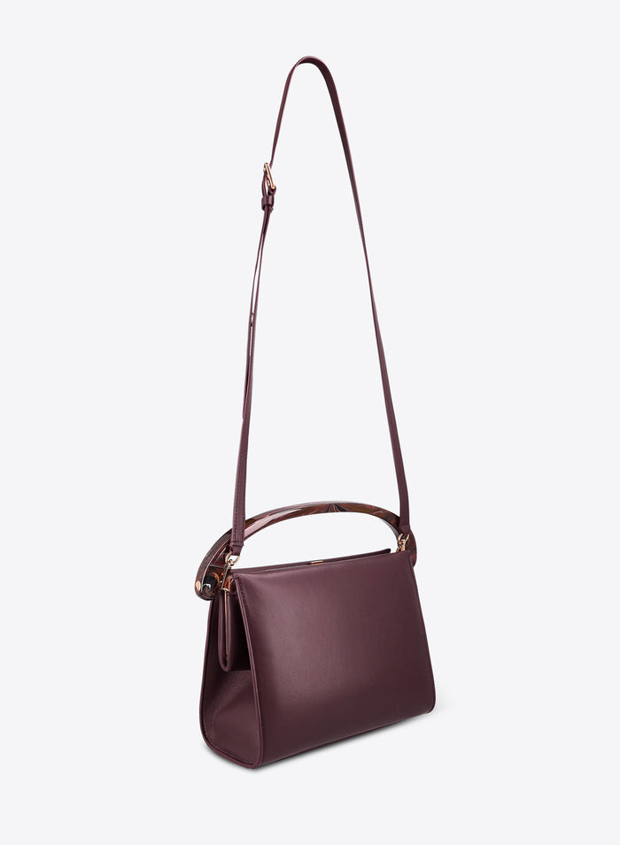 Burgundy leather handbag with a strap on a white background
