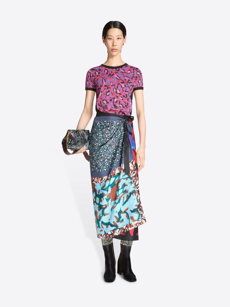 Model wearing a colorful outfit with a patterned top and skirt on a white background