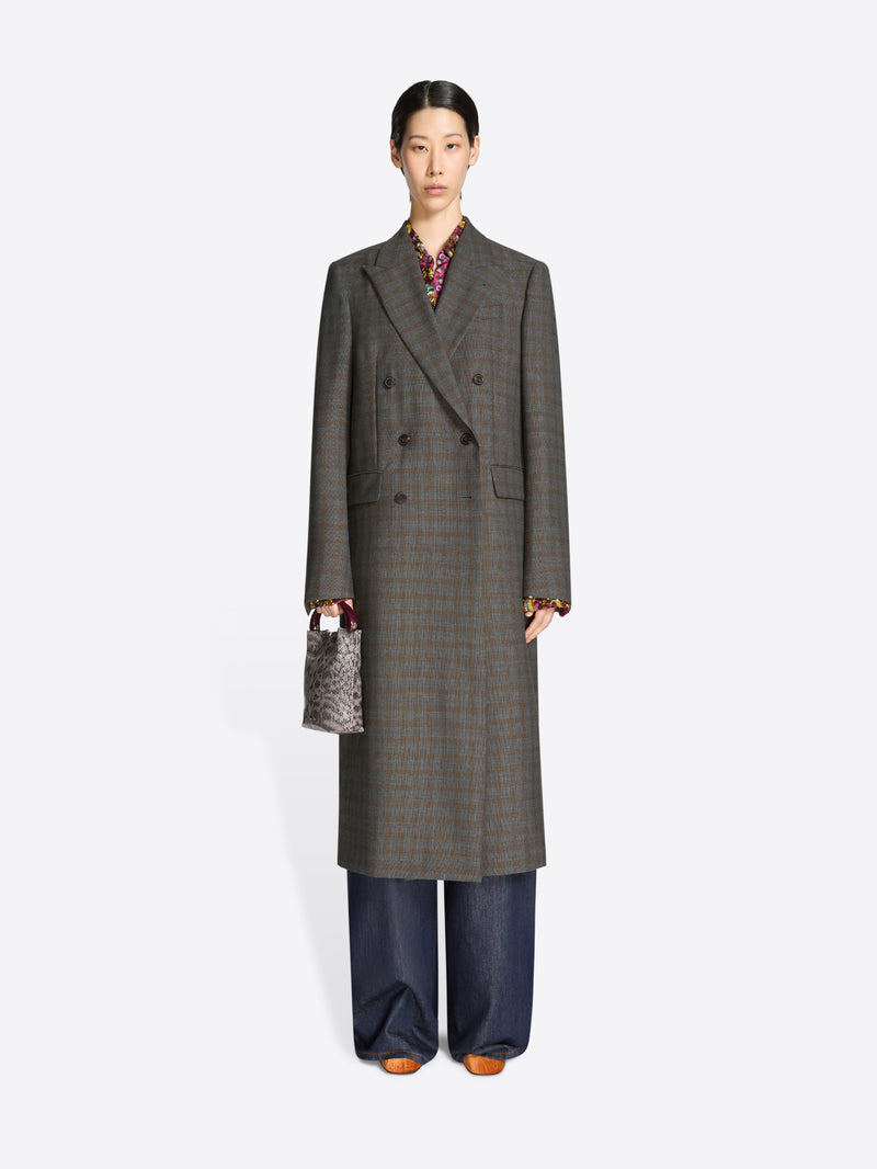 Person wearing a long gray checkered coat with a snake print handbag on a white background