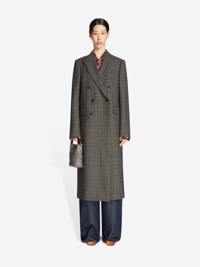 Person wearing a long gray checkered coat with a snake print handbag on a white background