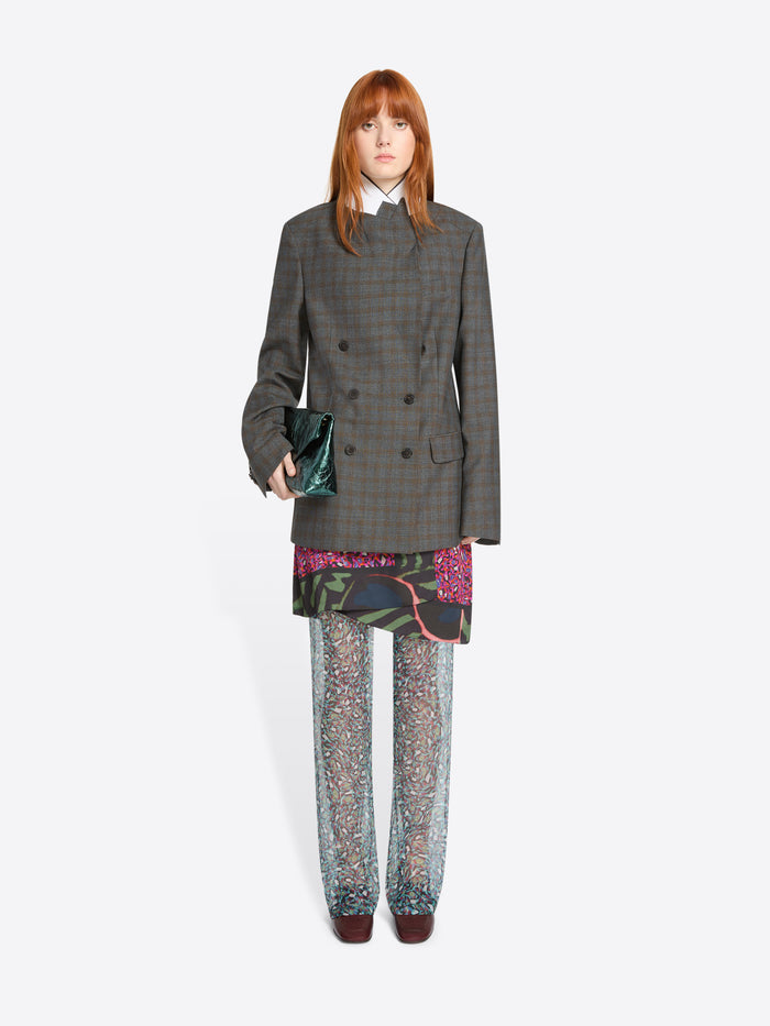 Person wearing a gray checkered coat with colorful pants with a handbag on a white background