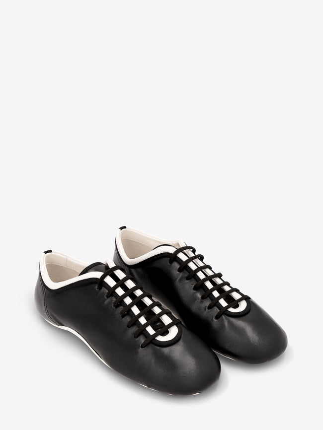 Pair of black sneakers with black laces on a light gray background