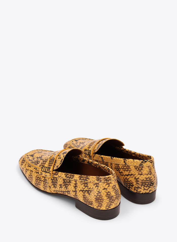Pair of yellow patterned loafers on a white background