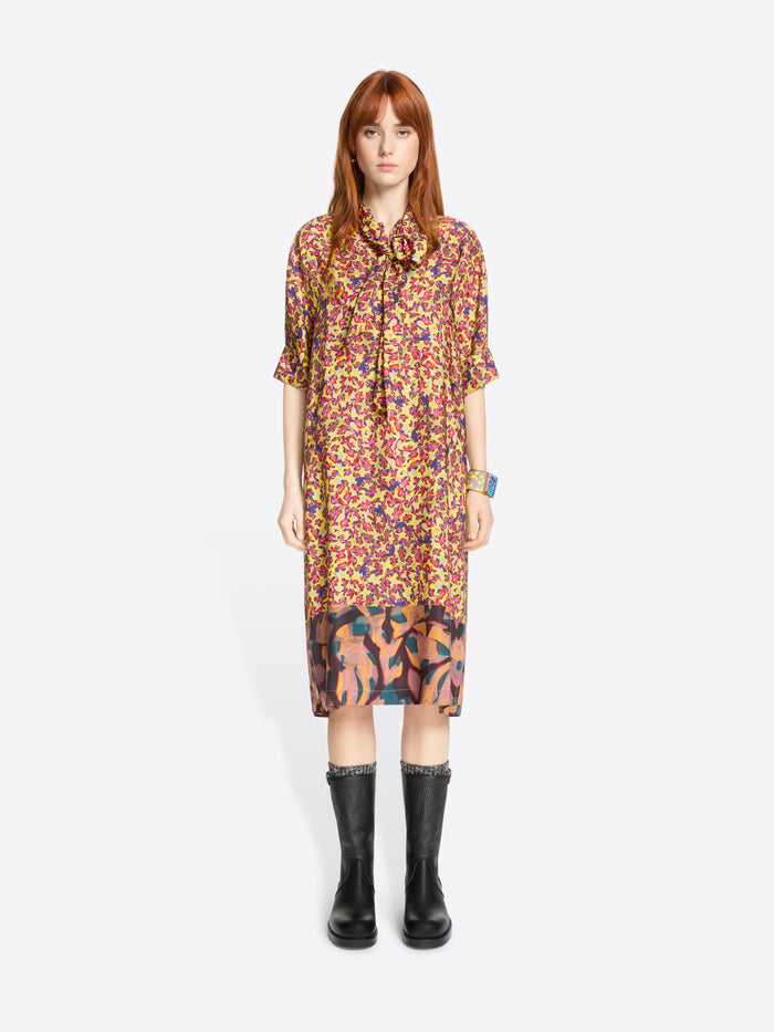 Woman wearing a colorful floral dress with black boots on a light grey background