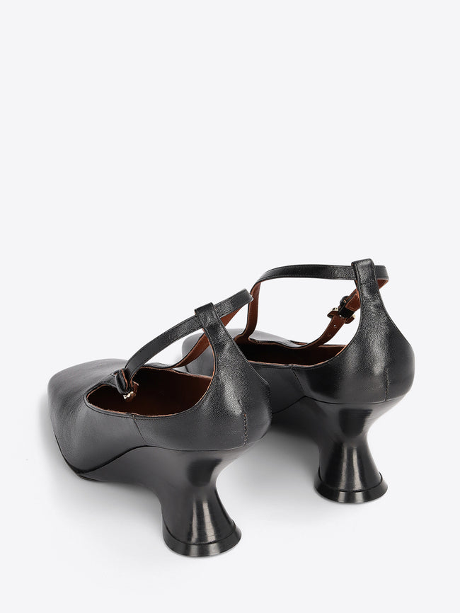A pair of black leather heels with a unique flared block heel and ankle strap on a light gray background.