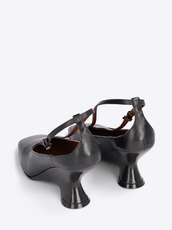 A pair of black leather heels with a unique flared block heel and ankle strap on a light gray background.