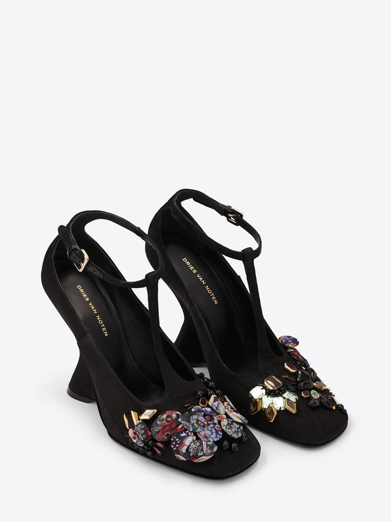 Black high-heeled shoes with floral embellishments on a white background