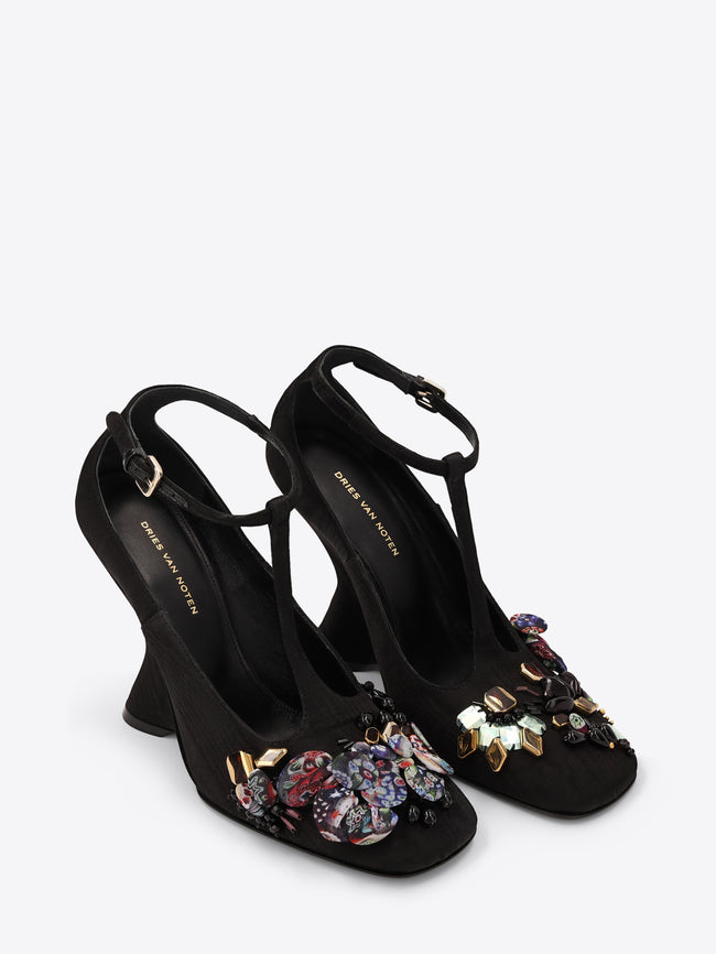 Black high-heeled shoes with floral embellishments on a white background