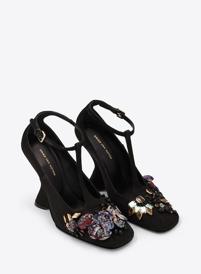 Black high-heeled shoes with floral embellishments on a white background