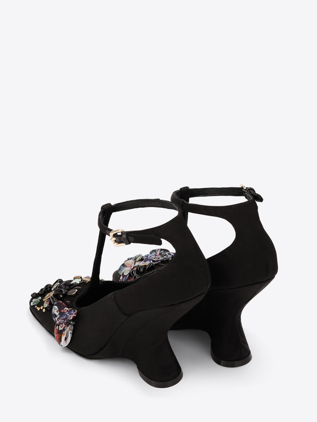 Black high-heeled shoes with floral embellishments on a white background