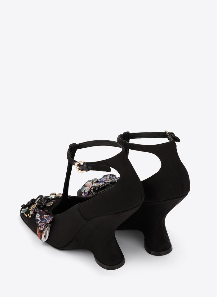 Black high-heeled shoes with floral embellishments on a white background