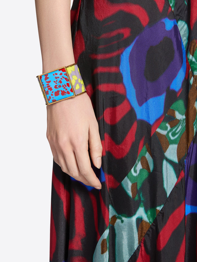 Colorful abstract patterned dress with a hand wearing a matching colorful bracelet.