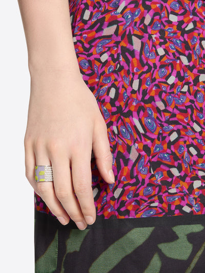 Close-up of a colorful patterned fabric with a hand wearing a ring.