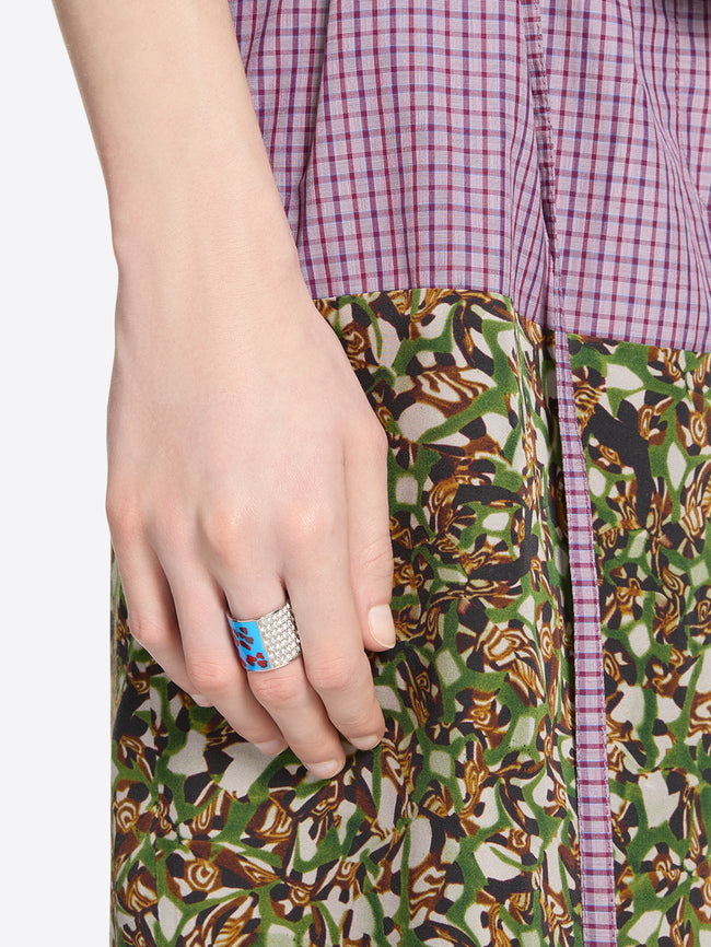 Close-up of a hand wearing a statement ring with sparkling crystals and a red-blue abstract pattern 
