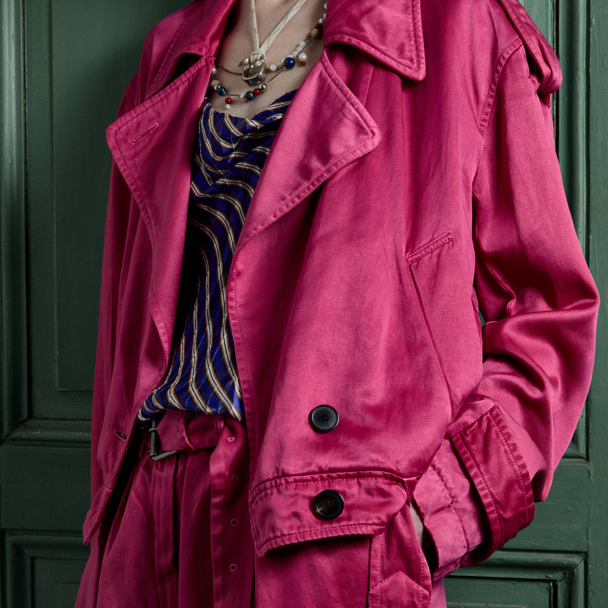 Pink jacket over a striped dress against a green door background - Dries Van Noten